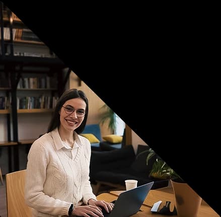 Profissional sorrindo em frente ao notebook em ambiente acolhedor.